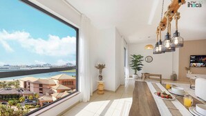 Ein modernes Wohnzimmer mit einem großen Fenster und Blick auf eine Stadtlandschaft sowie ein Gewässer.