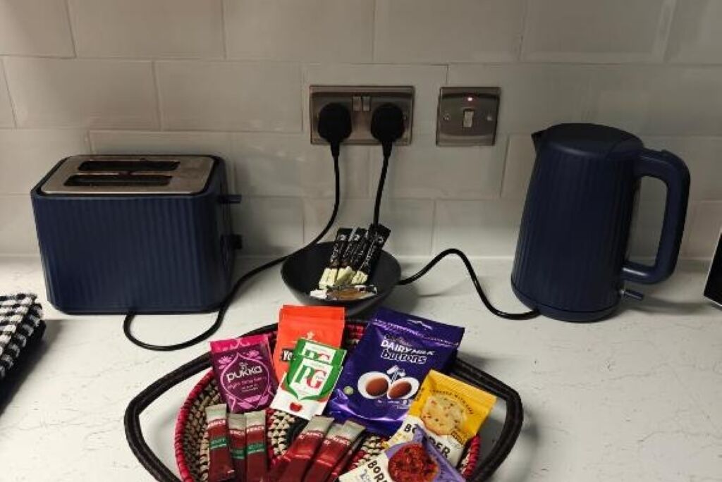 A kitchen counter with a toaster, kettle, and various food items.