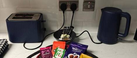 A kitchen counter with a toaster, kettle, and various food items.