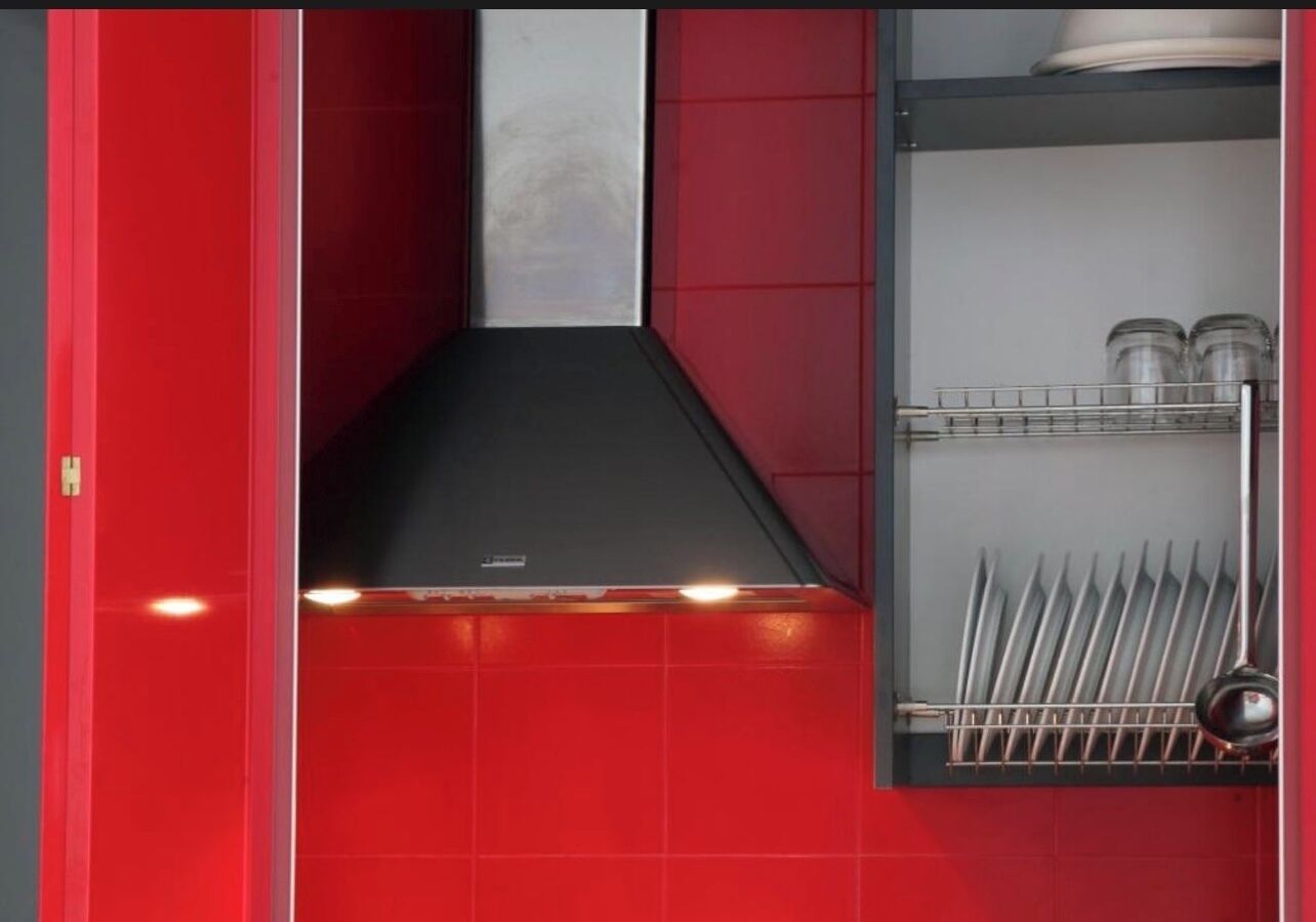 A kitchen with red walls, a black countertop, and a dish rack with utensils.