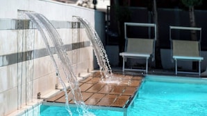 Ein Pool mit Wasserfall und zwei Liegestühlen.