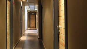 Ein Hotelgang mit Türen auf beiden Seiten, Fliesenboden und Decken mit Einbaustrahlern.