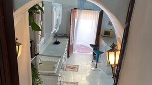 A kitchen with white cabinets, a sink, and a blue chair. There is a decorative rug with a kitchen scene on the floor. - Beautiful house, very comfortable, fully equipped, 500m from the beach, close to everything✅ (Boumerdes)