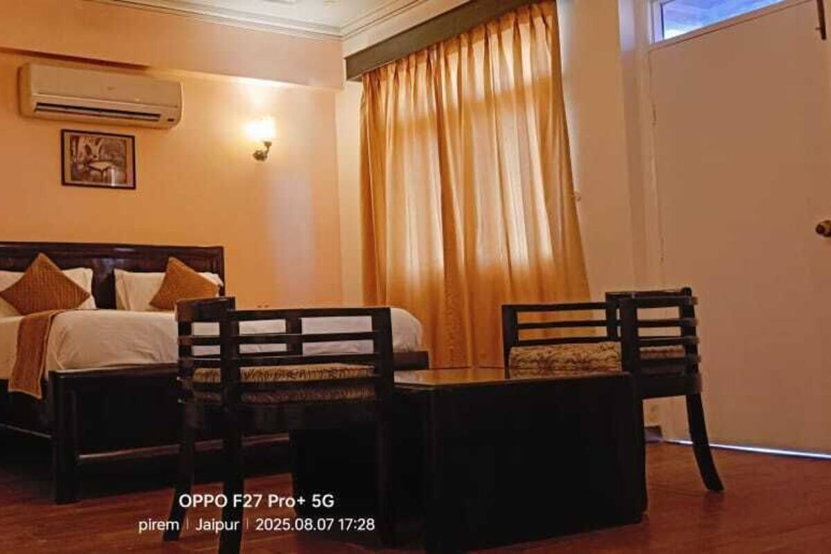 Ein Hotelzimmer mit Bett, Nachttisch, Stuhl und einem Fenster mit Vorhängen.