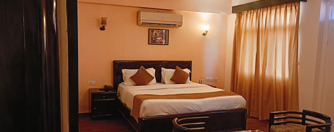 Una habitación de hotel con cama, mesita de noche, lámpara y una silla.