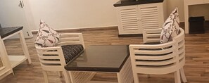 Un coin repas avec une table et quatre chaises blanches, chacune dotée d’un coussin.