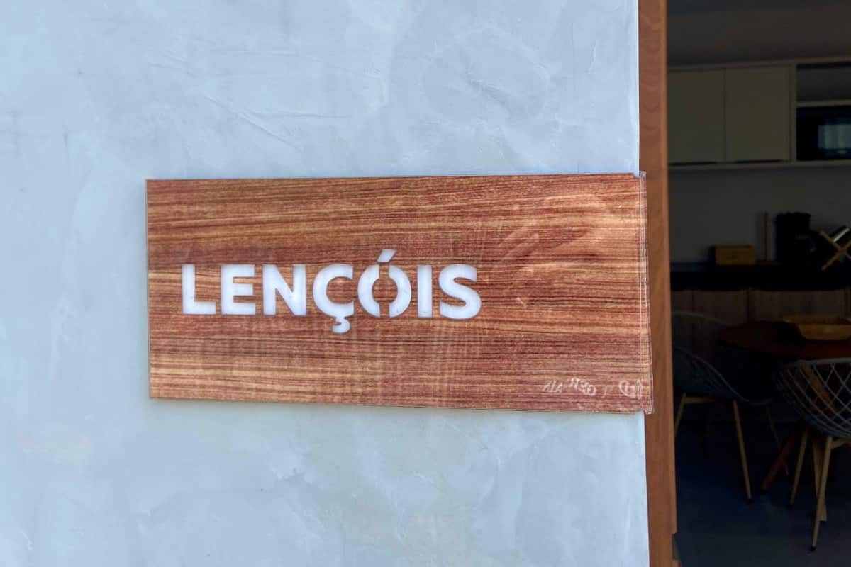 A wooden sign with the name "LENÇOIS" on a textured wall.