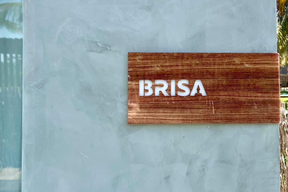 A wooden sign with the word "BRISA" on a textured wall.