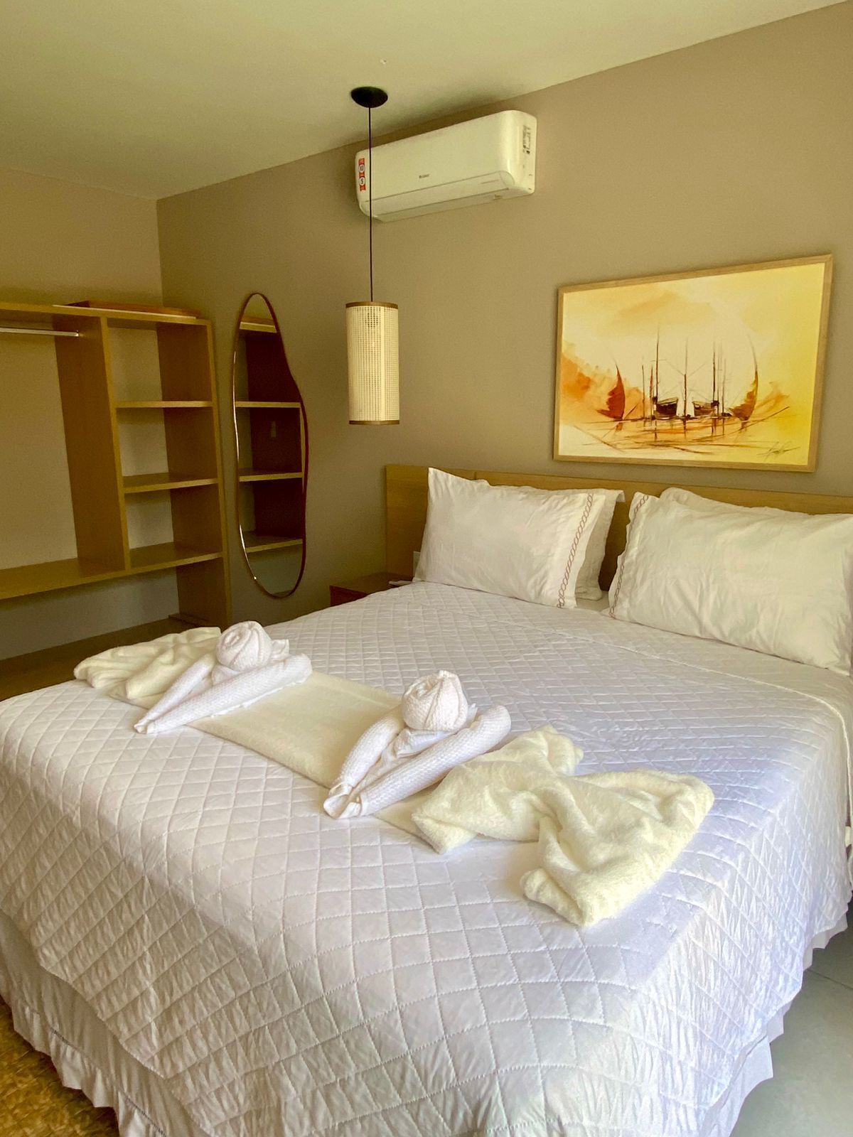 Habitació d'hotel amb un llit gran, un armari, un mirall, un aparell d'aire condicionat i un quadre a la paret.