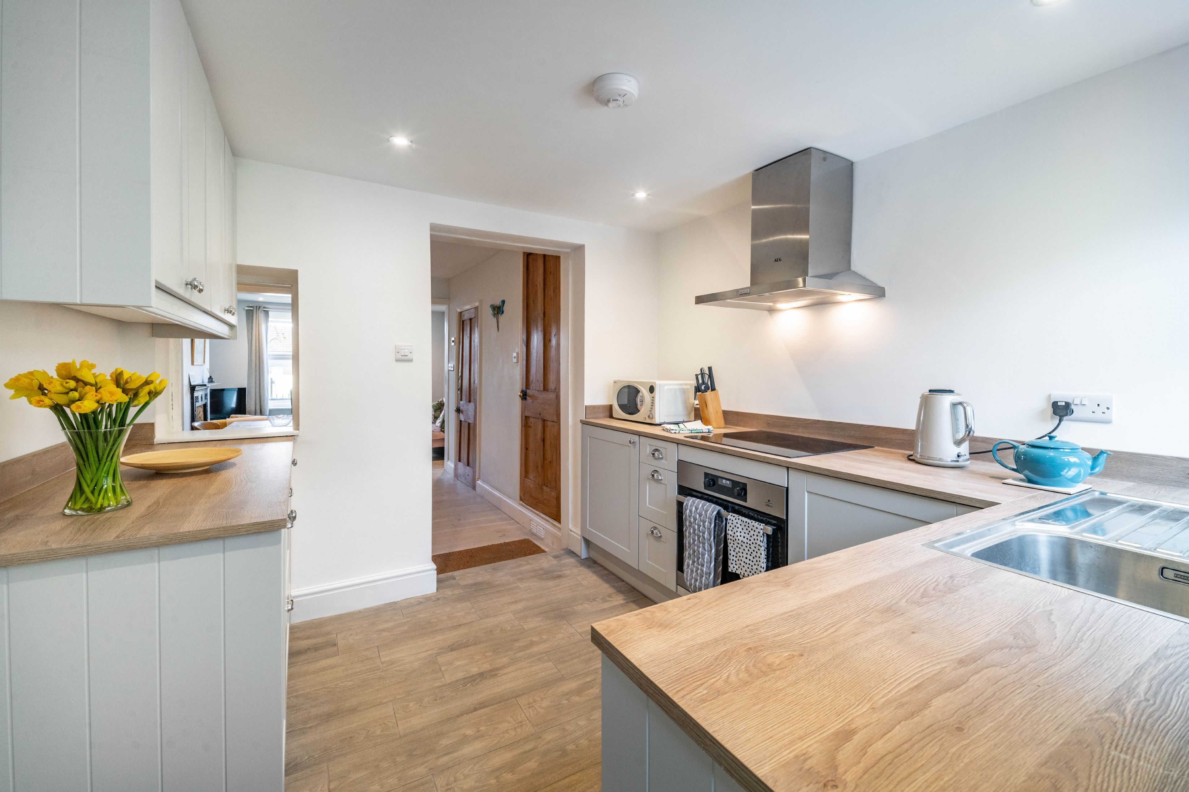 A modern kitchen with wooden countertops, white cabinets, and a stainless steel sink.