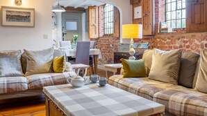 A cozy living room with a checkered table, plaid sofas, and a brick wall.