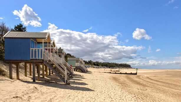 A beach with wooden structures, including a blue building with stairs and a green building.