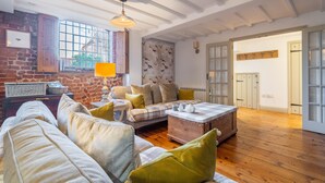 A cozy living room with a wooden floor, a plaid sofa, and a coffee table.