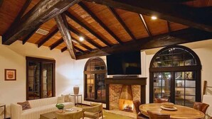 A cozy living room with a fireplace, a television, and a dining area with wooden furniture.