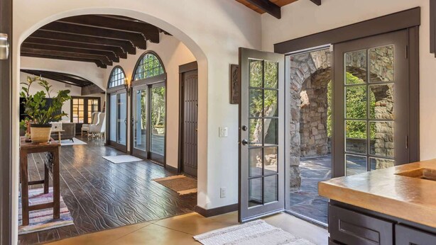 A spacious interior with a high ceiling, arched doorways, and a stone wall.
