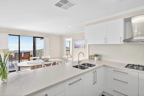 A modern kitchen with white cabinets, a double sink, and a gas stove.