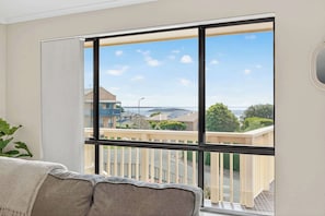 A room with a large window, a view of a residential area, and a balcony.
