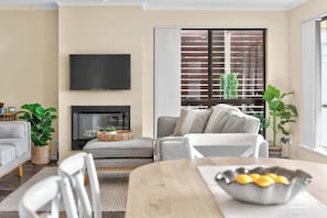 Un salon avec une cheminée, un canapé, un téléviseur et un coin repas.
