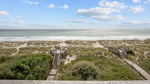 A beach view with wooden walkways and a sandy path leading to the ocean. - Cassimir West | Stunning Oceanfront Duplex Retreat (Emerald Isle)