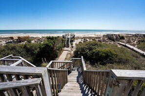 A wooden staircase leading to beach access with wooden railings and benches. - Cassimir West | Stunning Oceanfront Duplex Retreat (Emerald Isle)