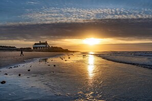 A beach with a building and a sunset. - Lifeboat Cottage, Brancaster, Norfolk (Brancaster)