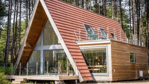 A modern A-frame cabin with large windows, a deck, and a forest backdrop. - Liz's Lodge, Weybourne, Norfolk (Weybourne)