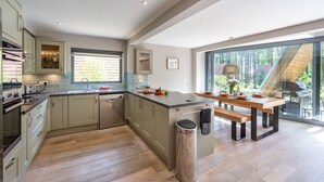 A modern kitchen with a large island, built-in appliances, and a view of the outdoors. - Liz's Lodge, Weybourne, Norfolk (Weybourne)