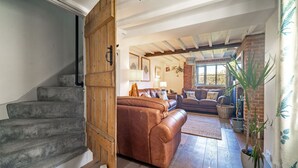 Un escalier menant à un espace de vie comprenant un canapé en cuir marron, une porte en bois et un mur en briques.
