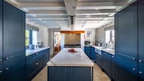 Une cuisine moderne avec des meubles de couleur bleu foncé, un îlot en marbre et un pare-feu décoratif.
