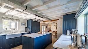 Une cuisine moderne avec des meubles de couleur bleu foncé, un grand îlot central et une bouilloire en acier inoxydable.