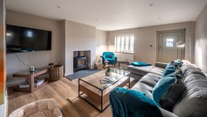 Un salon moderne avec un téléviseur à écran plat, une cheminée, un canapé et une table basse.