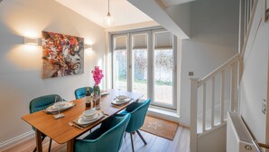 Un coin repas avec une table en bois, des chaises de couleur turquoise et un grand tableau abstrait accroché au mur.