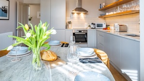 A modern kitchen with white cabinets, a marble countertop, and a built-in oven.
