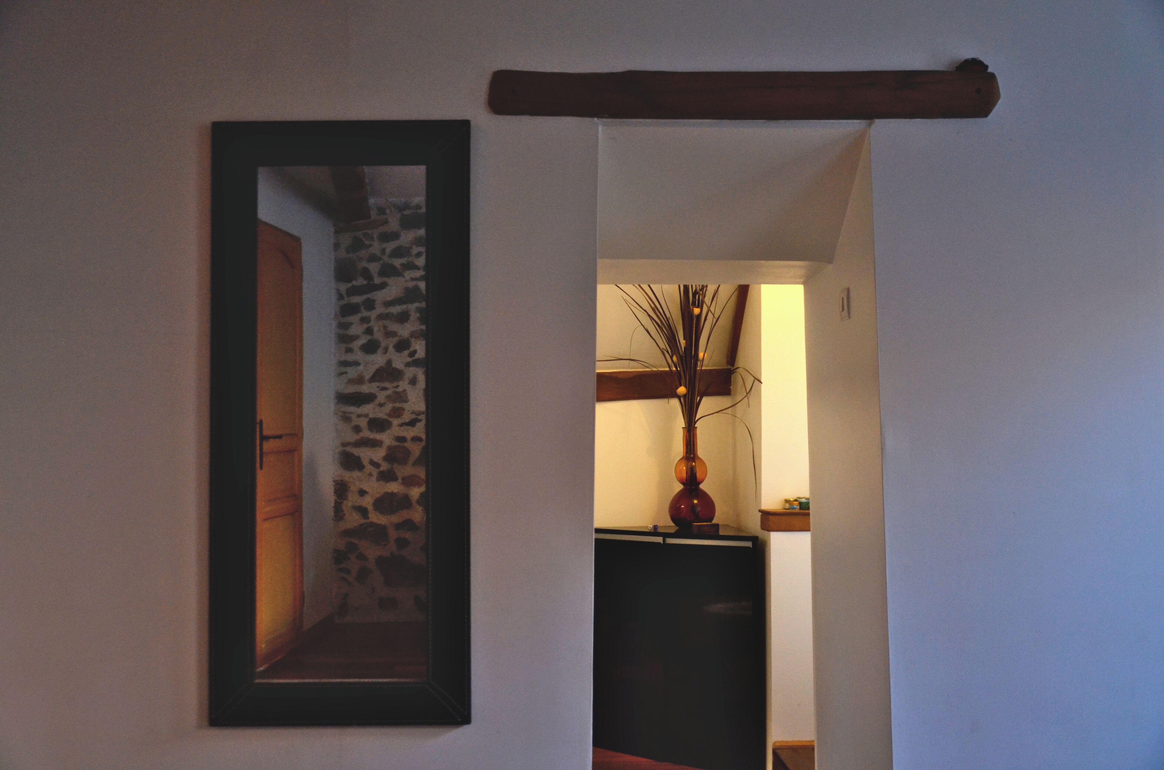 Un vano que da a un cuarto con pared de piedra y un espejo a la izquierda.