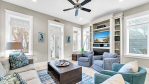 A living room with a sofa, armchairs, a coffee table, and a TV.