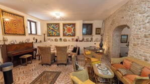 Una sala de estar acogedora con muebles de mimbre, un piano y una pared de piedra.