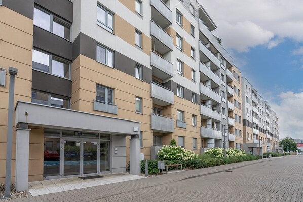 A multi-story residential building with balconies, a gated entrance, and a landscaped area with flowers. - AS HOME Tęczowa 89 (Wrocław)