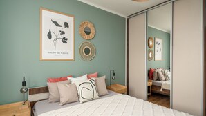 Ein Schlafzimmer mit einem Bett, Nachttischen, einem Spiegel und Wandbildern.