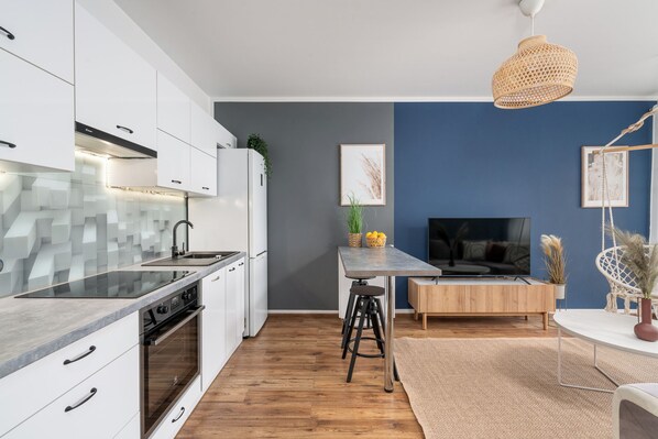 A modern kitchen with white cabinets, a built-in oven, and a glass backsplash. - AS HOME Tęczowa 89 (Wrocław)