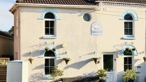 Un edificio a due piani con facciata beige, infissi blu e un cartello con la scritta "Nola Welcome".