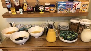 Un bancone della cucina con diversi alimenti e contenitori, tra cui ciotole, una brocca e scatole di cereali.