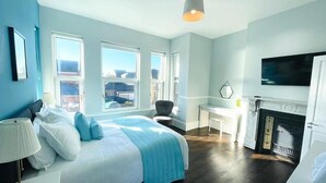 Un dormitorio moderno con una cama grande, un escritorio, una chimenea y un televisor.