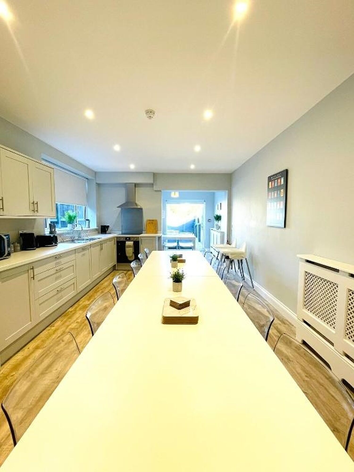 Une cuisine moderne dotée d’un grand îlot central, de meubles blancs et d’un îlot central intégrant un four.