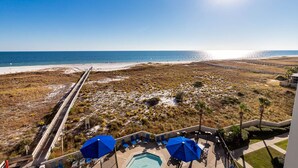 Een strandhotel met zwembad, terras en een boardwalk naar het strand.