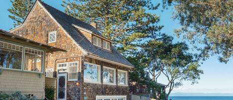 A coastal house with a brick facade, a garage, and a view of the sea.
