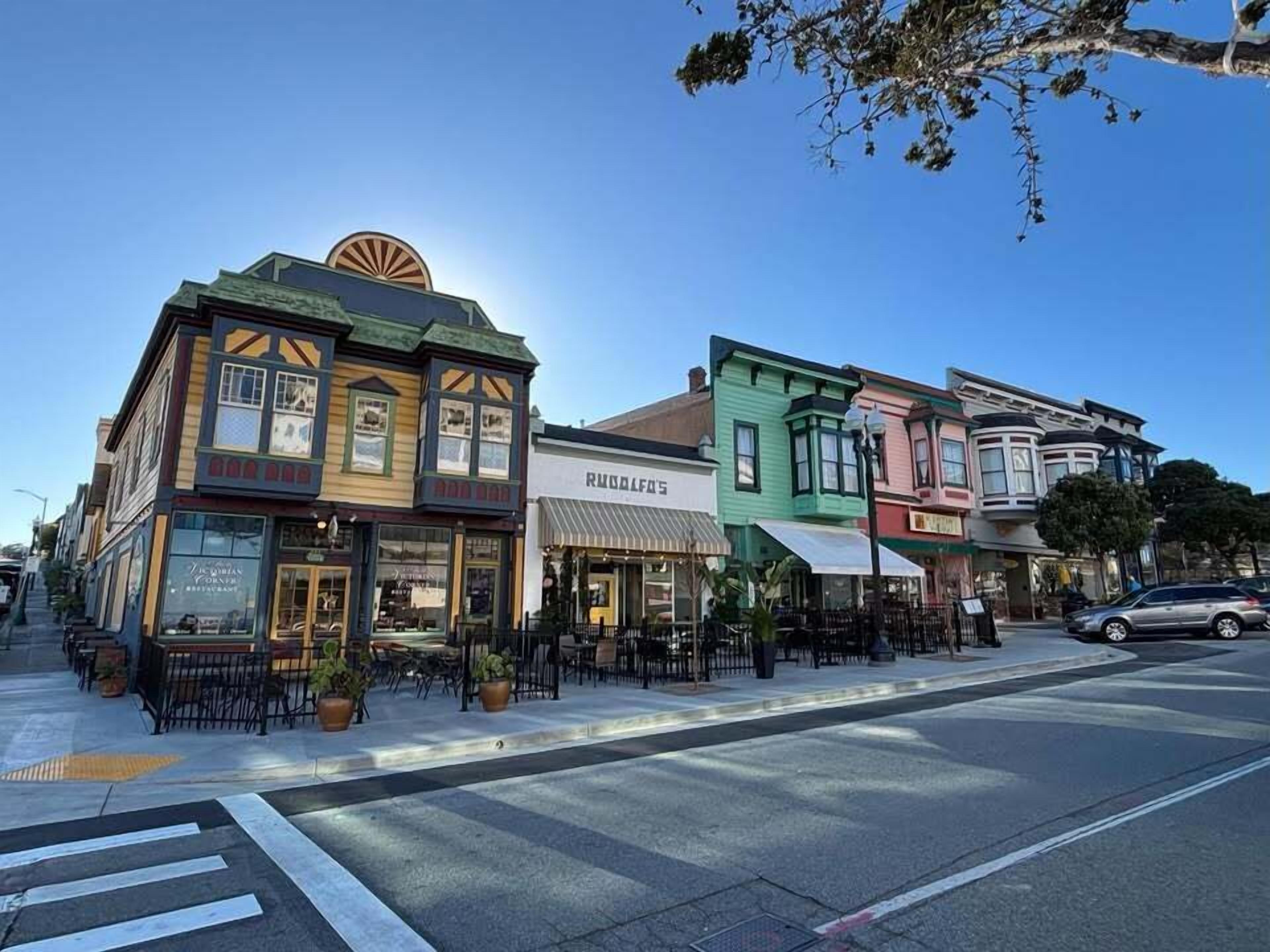 Une rue bordée de bâtiments aux couleurs vives, dont un restaurant appelé « RUDOLPH’S ».