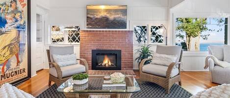 Una sala de estar con chimenea, muebles de mimbre y un cartel grande en la pared.