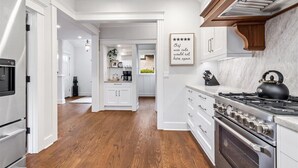 A modern kitchen with white cabinetry, a wooden floor, and a stainless steel stove.
