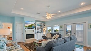 A spacious living room with a fireplace, a large gray sofa, and a bookshelf. - Casa Azul 3 Bedroom Home (Port Bolivar)