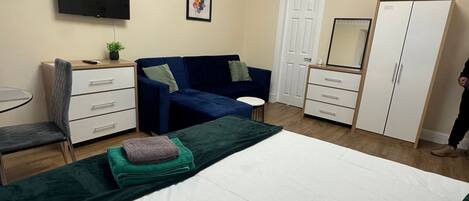 A bedroom with a bed, a TV, a dresser, a wardrobe, and a door.